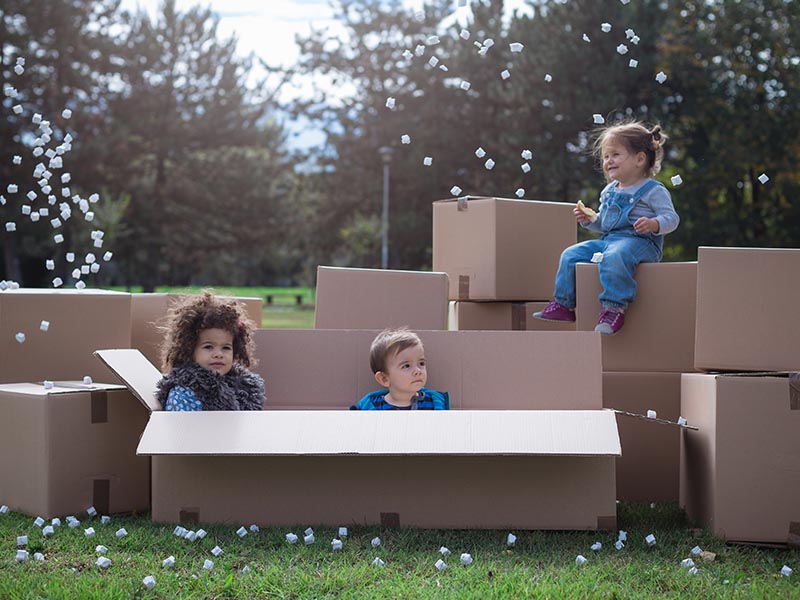 young kids playing in moving boxes outside
