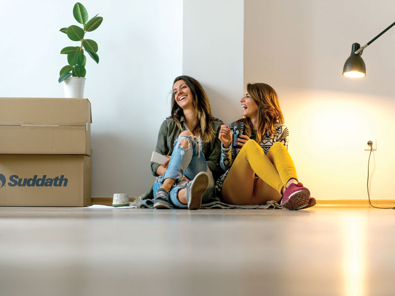 women sitting next to moving boxes