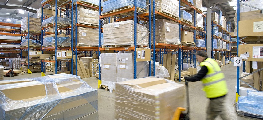man pushing pallet in supply chain logistics warehouse