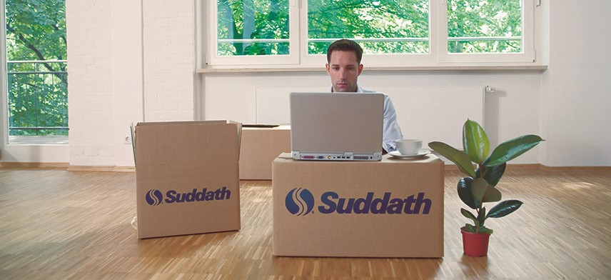 man working on laptop surrounded by moving boxes