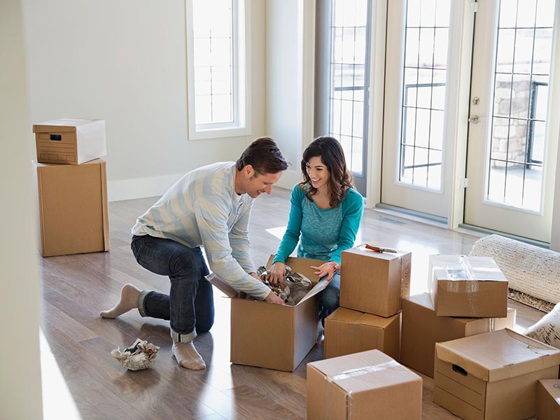 couple packing moving boxes together in home