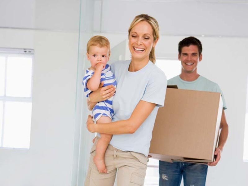 family with young child carrying moving box