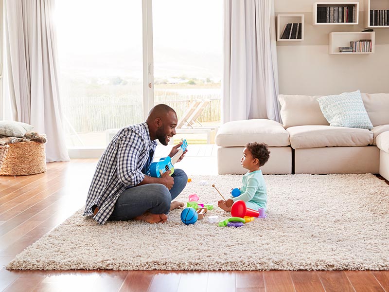 father and baby playing with toys on carpet in living room