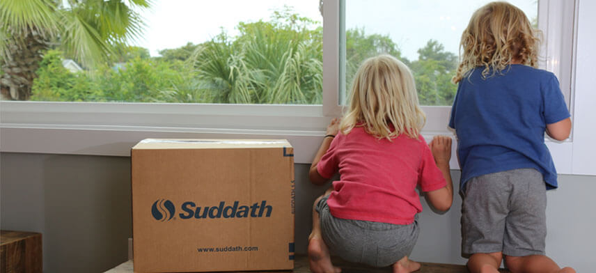 kids looking through window next to suddath moving box