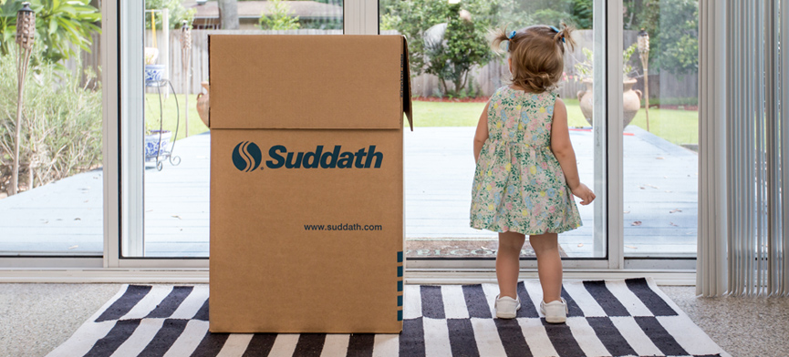 female toddler next to moving box looking outside