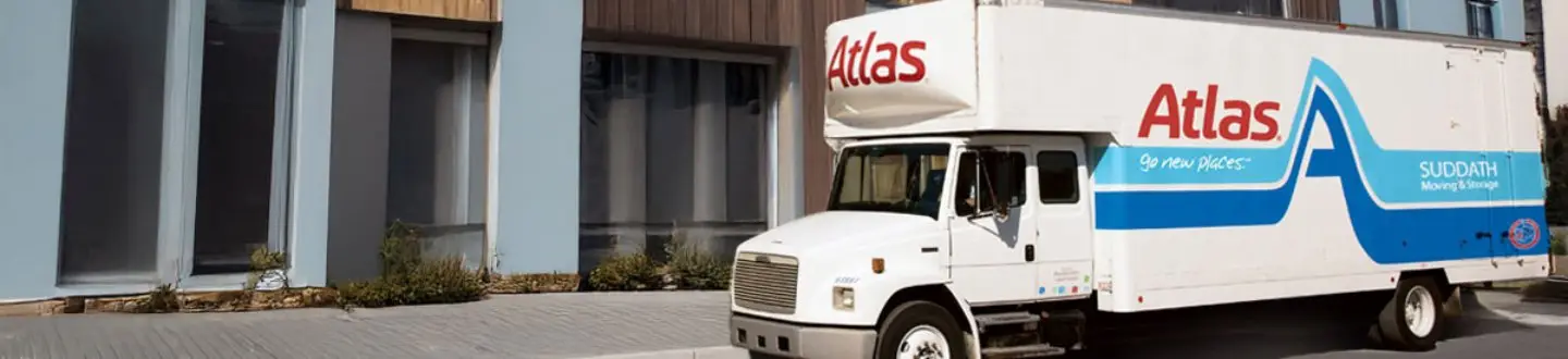 Atlas moving truck parked in front of a modern building with tall windows