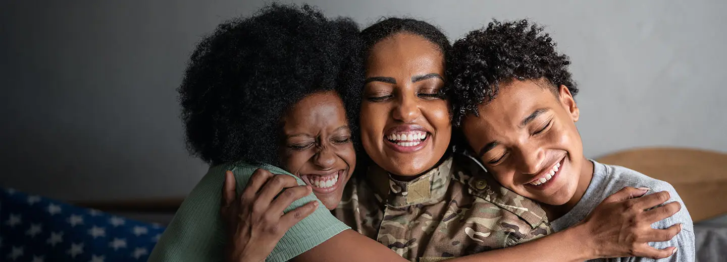 Smiling military parent hugging children during homecoming