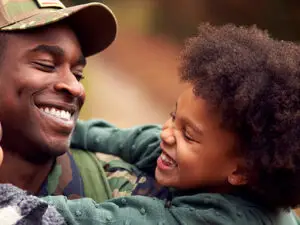 Smiling military parent embracing two joyful children outdoors