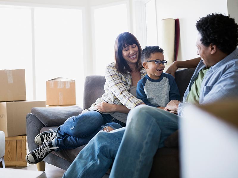 family relaxing on couch after home move with moving boxes
