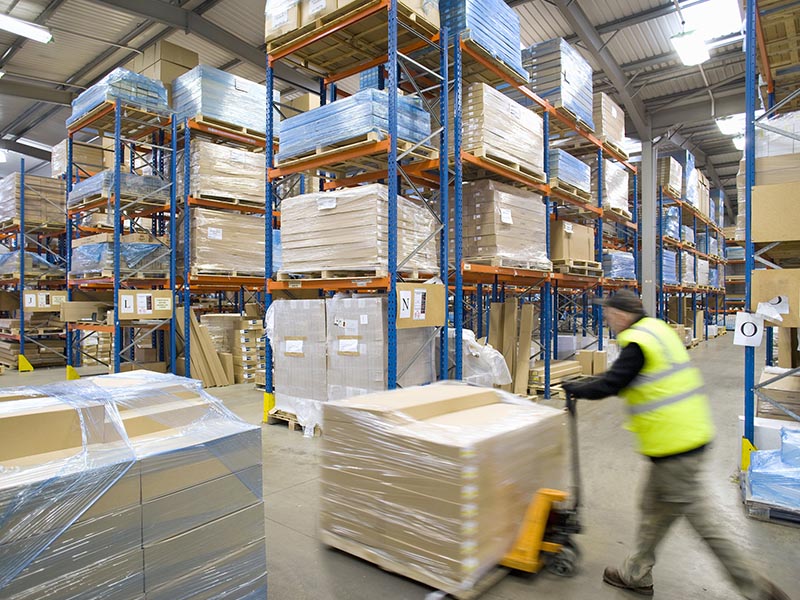 man moving pallet at supply chain logistics warehouse