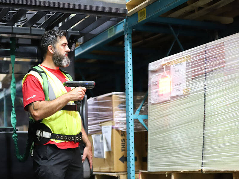 man scanning product on pallet in logistics warehouse